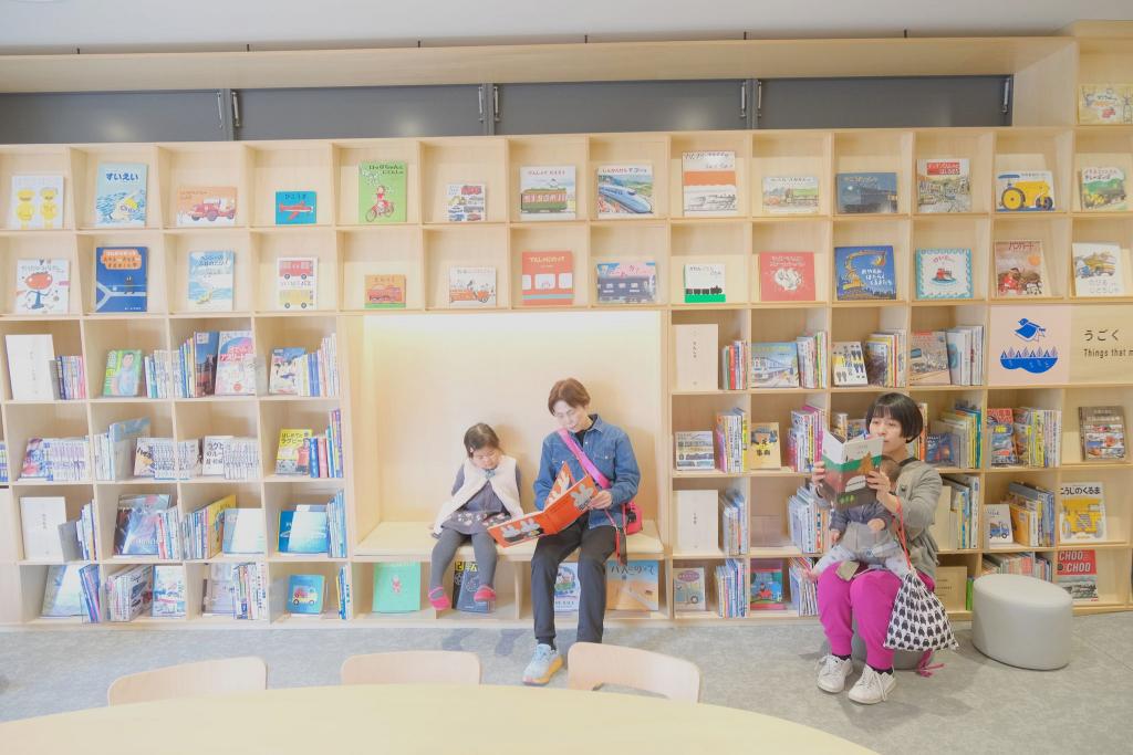 本棚の空きスペースのベンチで本を読む家族も